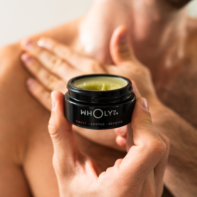 Person holding a jar of balm jar near their shoulder